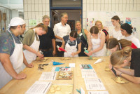 Azubi Muhamad (l.) aus dem Iran gab den Gymnasiasten Deko-Tipps in der Backstube; Thomas Mörtel, Ralf Dambier, Michaela von Wittke und Ulrike Wenning (hinten v.l.) begutachteten deren Werke.